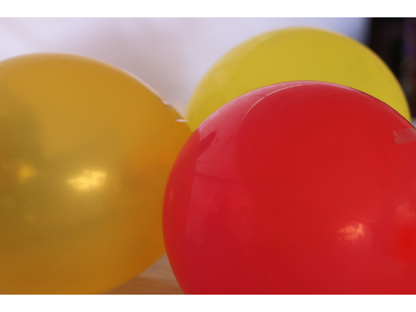 close up image of three shiny balloons one red one yellow and one gold