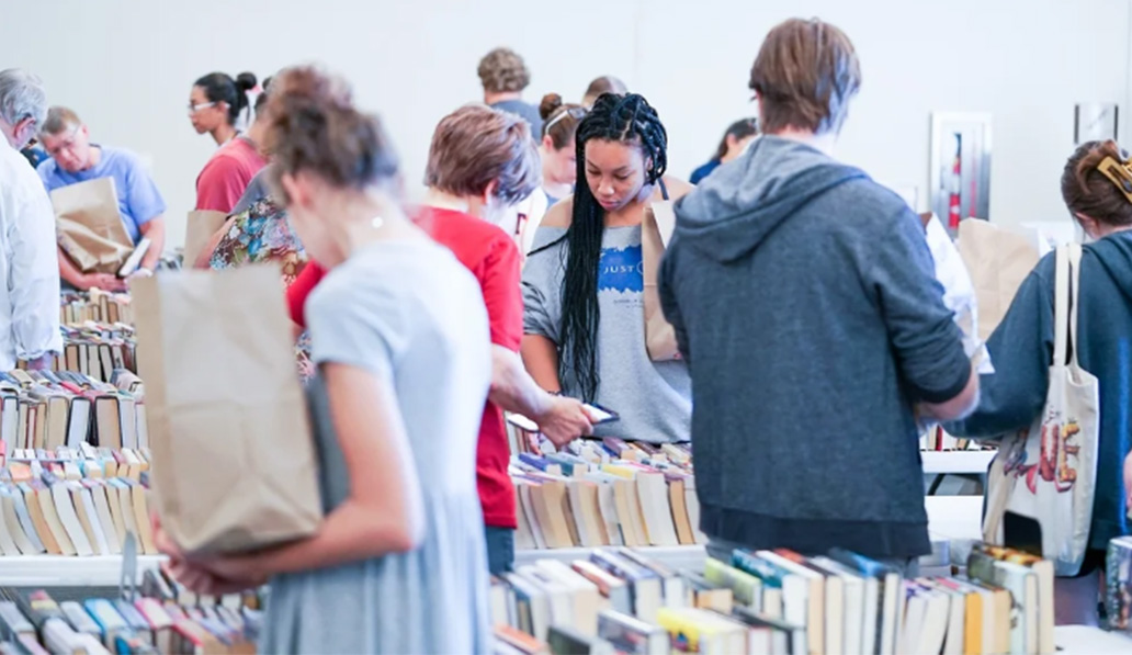 People browsing tables of books at a book sale.
