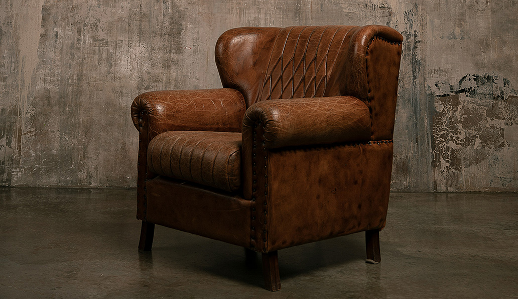 Leather armchair in dark cement room.
